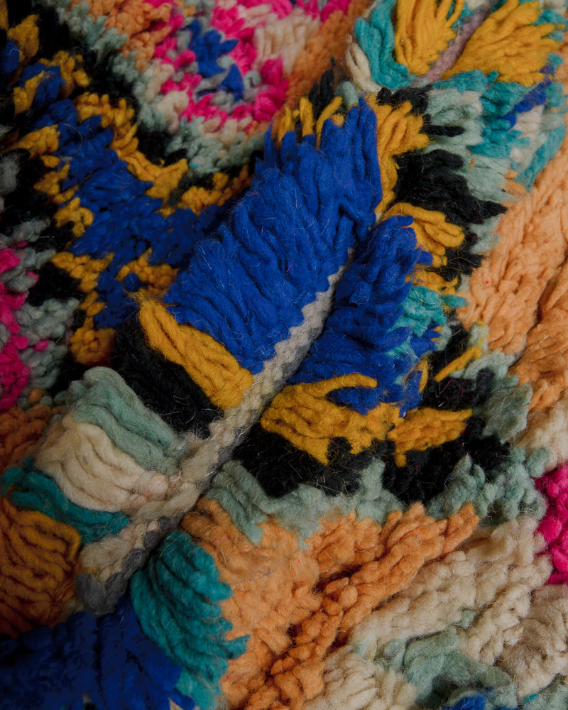Close up of wool rug made of different shades of blue , yellow, orange and black.