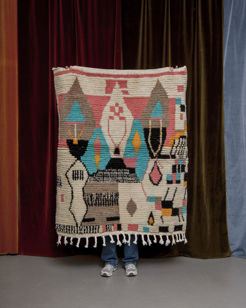 Berberlin Vintage rug held up in front of velvet curtains. 