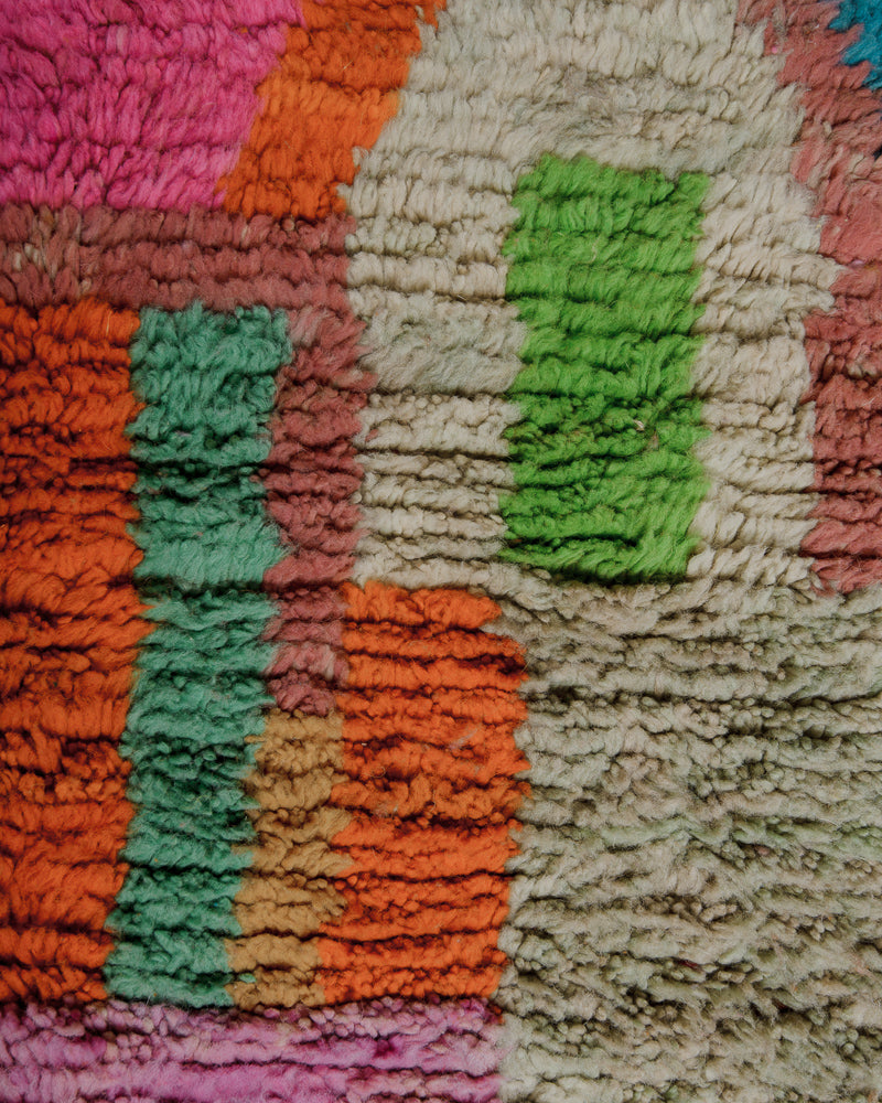 Close up of surface of wool rug with pink, green, mint and orange.