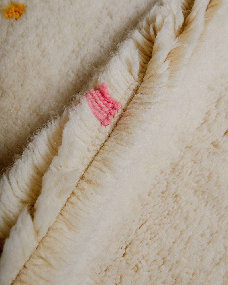 Close up of Berberlin Finest rug showing fluffy pile made of cream wool and pink wool detail.