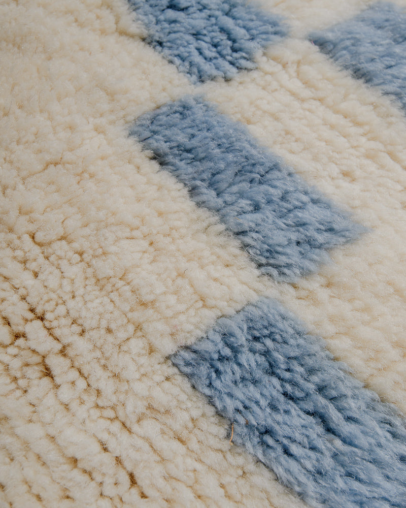 Close-up of cream wool rug with geometric design in sky blue.