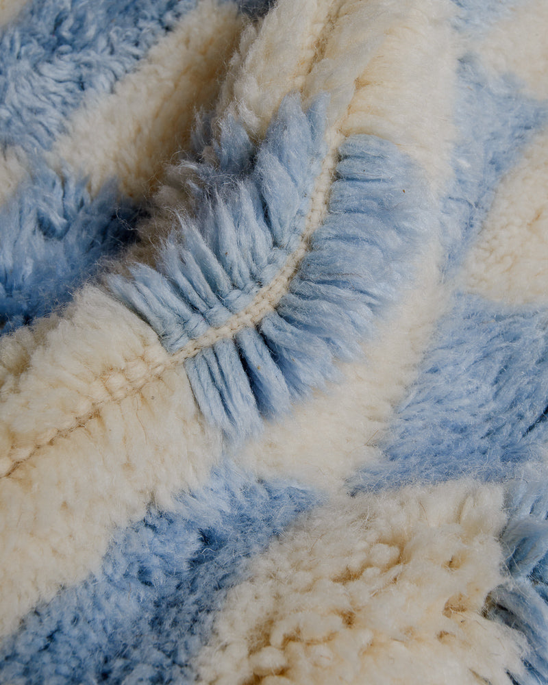 Close-up of cream wool rug with sky blue design.