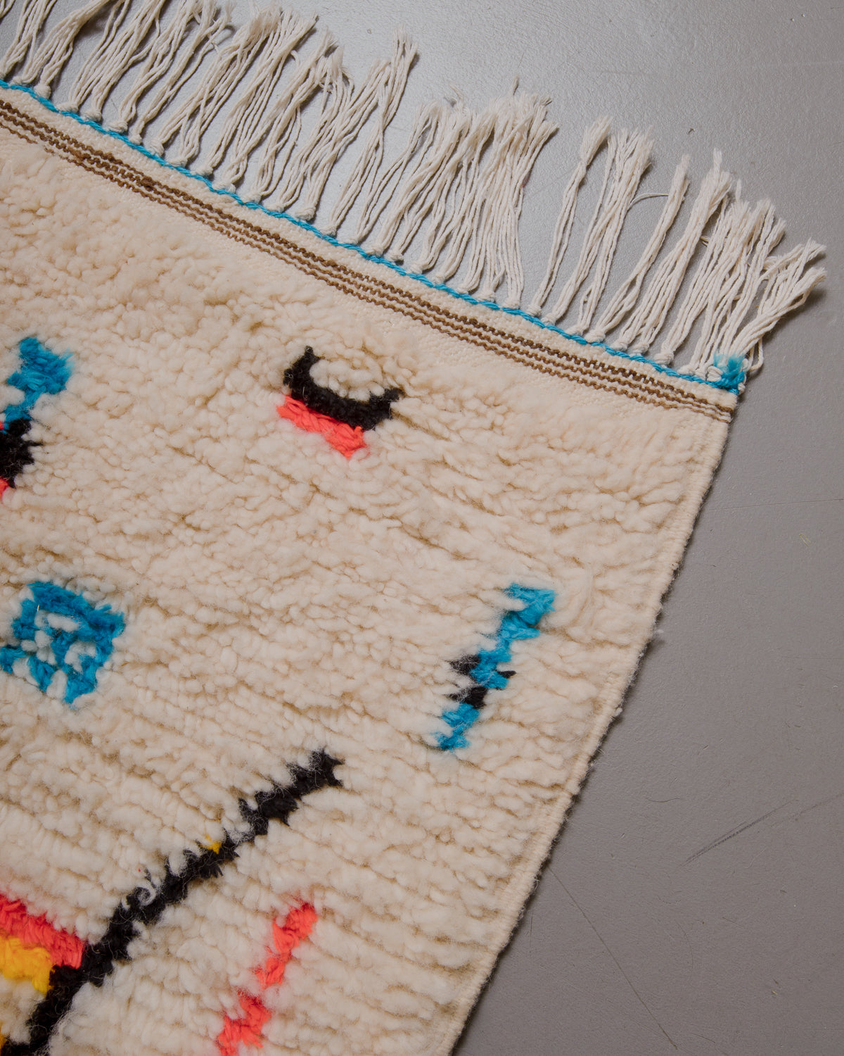 Corner of azilal rug with white cotton fringe.
