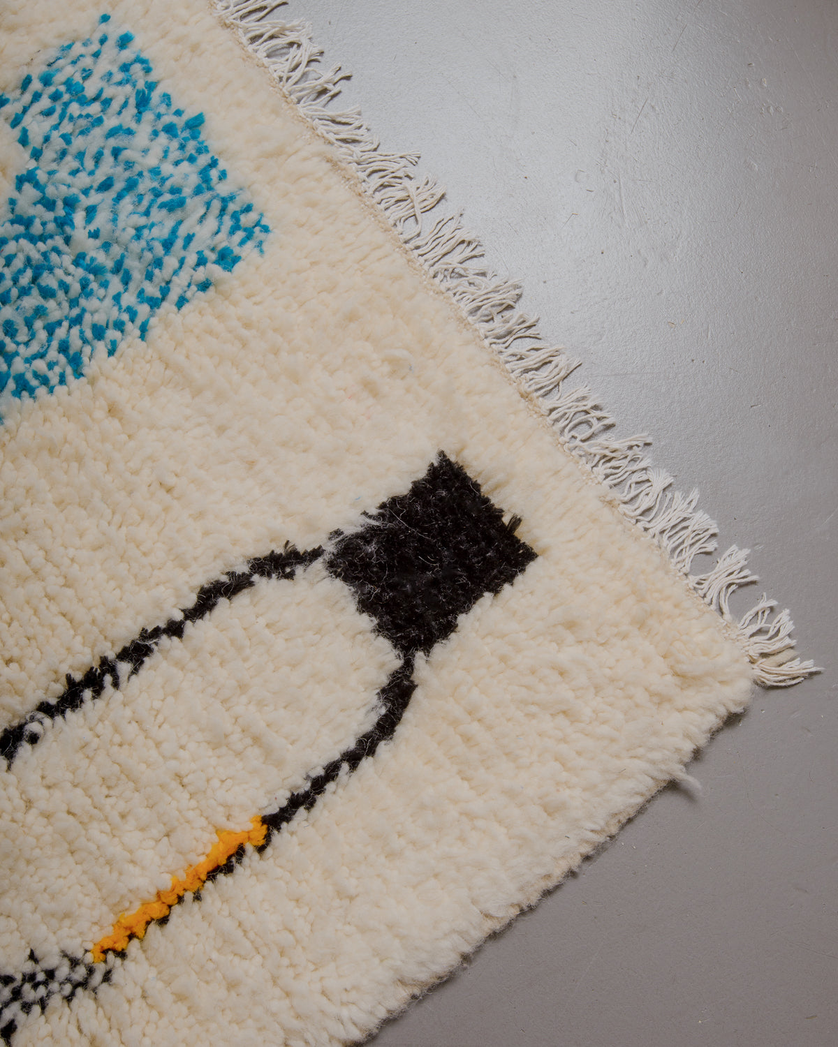 Corner of azilal rug with white cotton fringe.