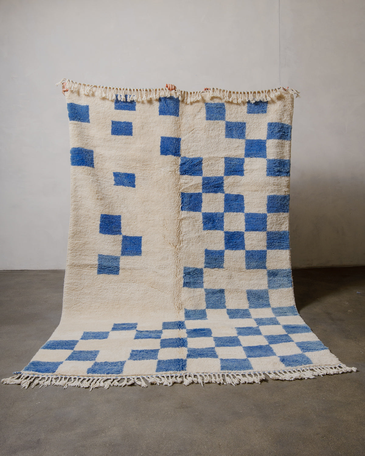Checkered rug with blue and cream wool on a plain background