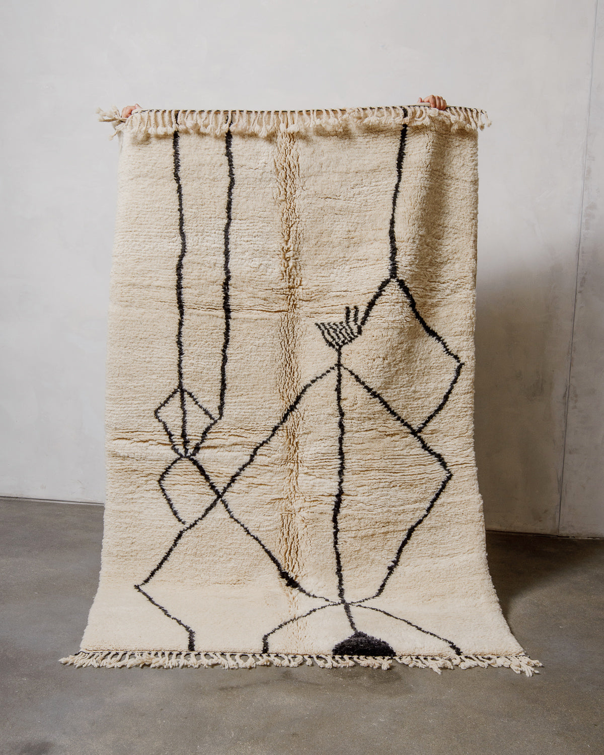 Cream wool rug with black minimalist design on a plain background