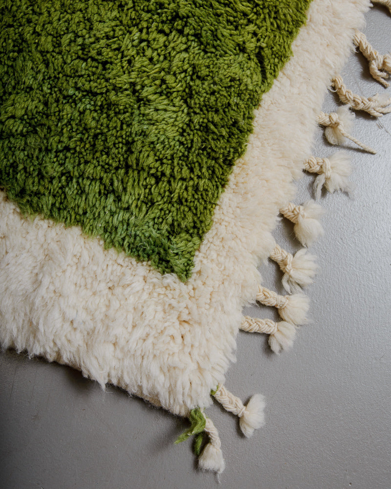 Corner of rug with short tassels in green and cream wool