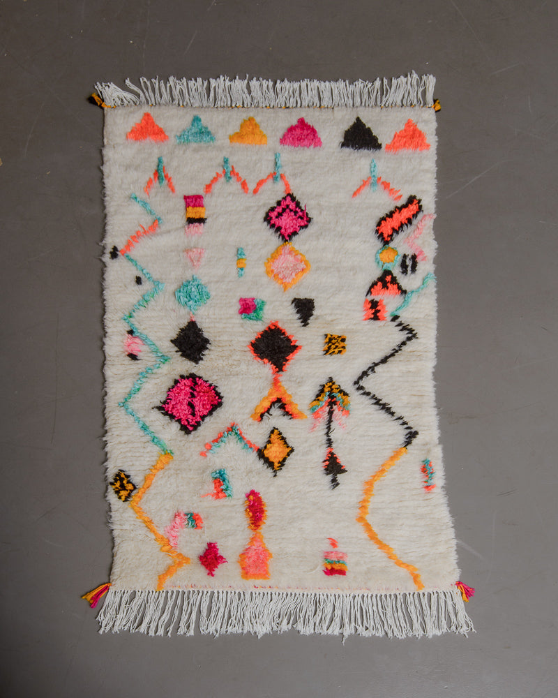 Brightly coloured azilal rug on grey floor.