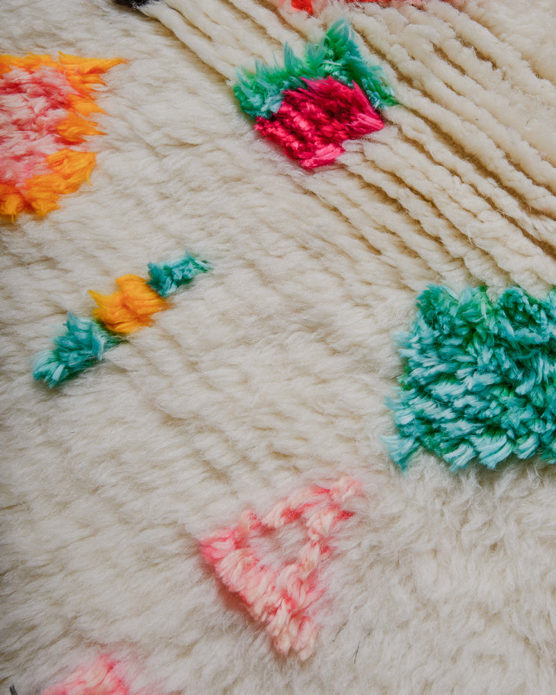 Close up of azilal rug showing fluffy pile made of cream wool and colourful cotton. 