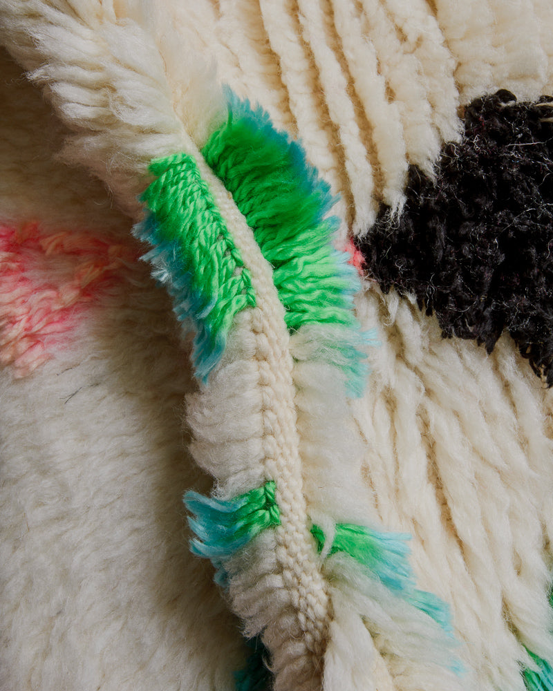 Close up of azilal rug showing fluffy pile made of cream wool and colourful cotton. 