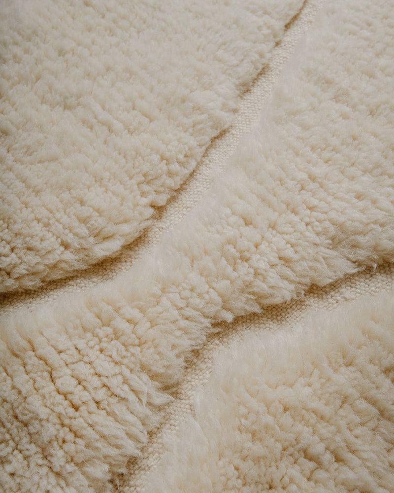 Surface or cream wool rug with woven patterns. 