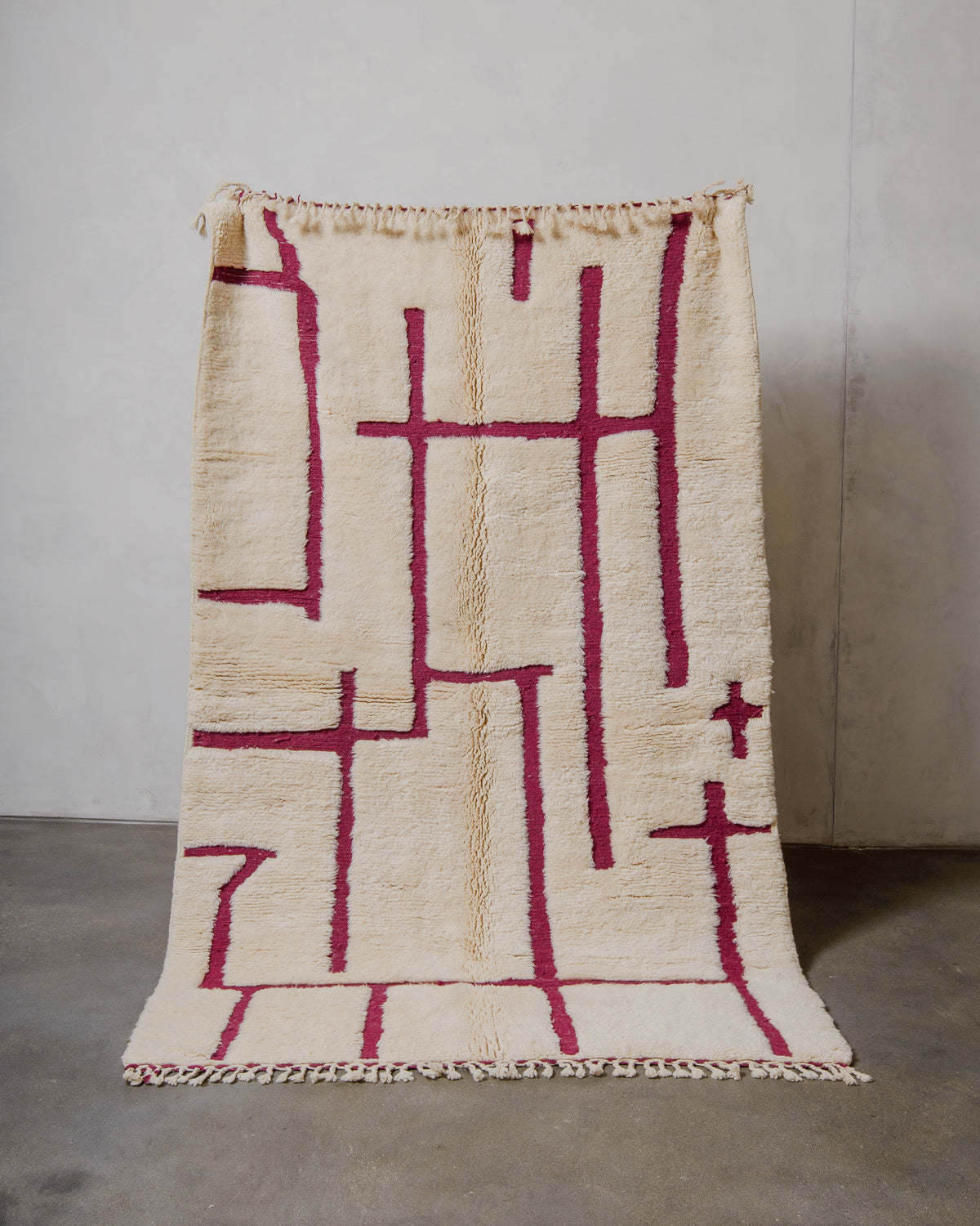 Cream and magenta geometric patterned rug on a neutral background