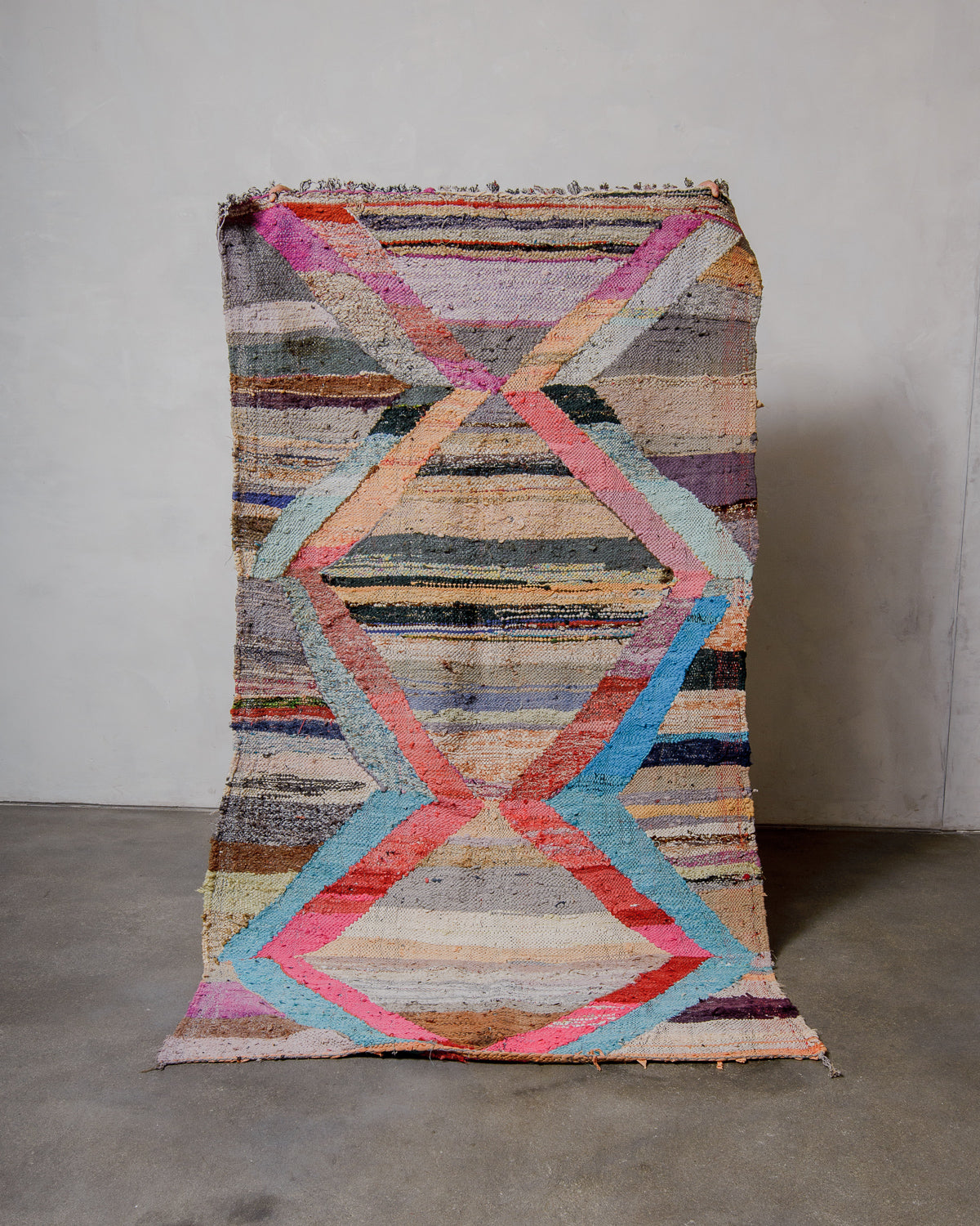 Multicolored geometric-patterned rug on a plain floor with a neutral background