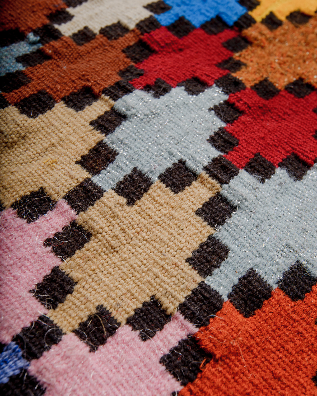 The pattern on a vintage Berberlin Kelim rug made with coloured wool and black accents.