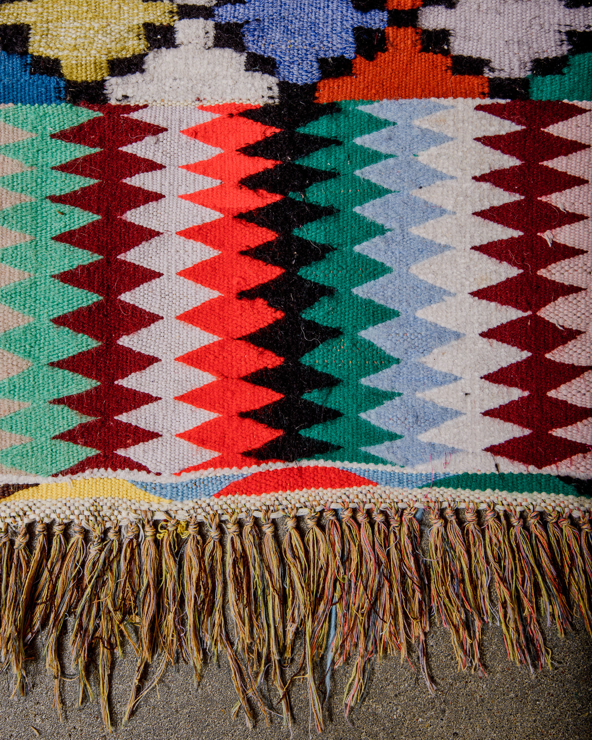 Edge of Vintage Kelim runner rug with three different patterns made of brightly coloured wool and cotton tassels.