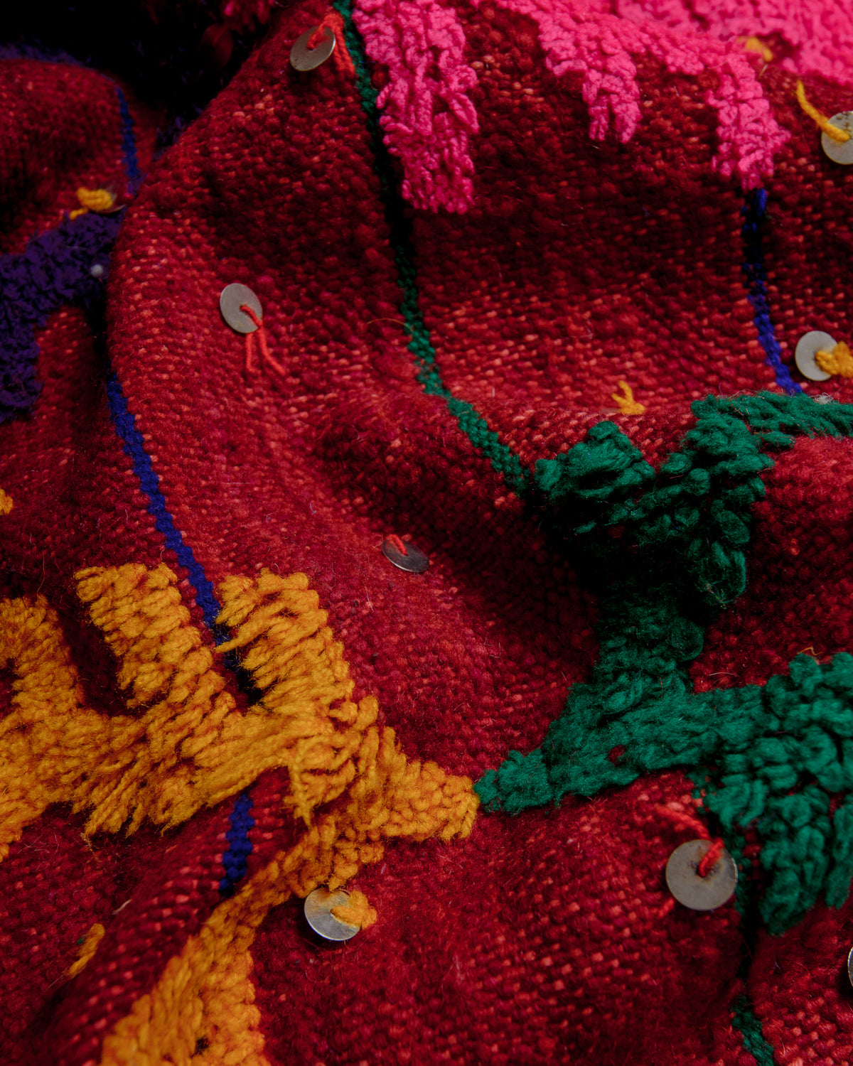 Close up showing the embroidered, raised details and metal beads on the surface of the rug.