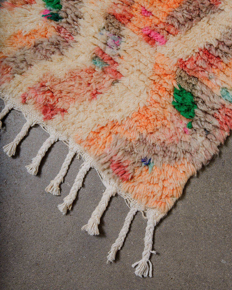Colourful woven rug with tassels on a grey surface