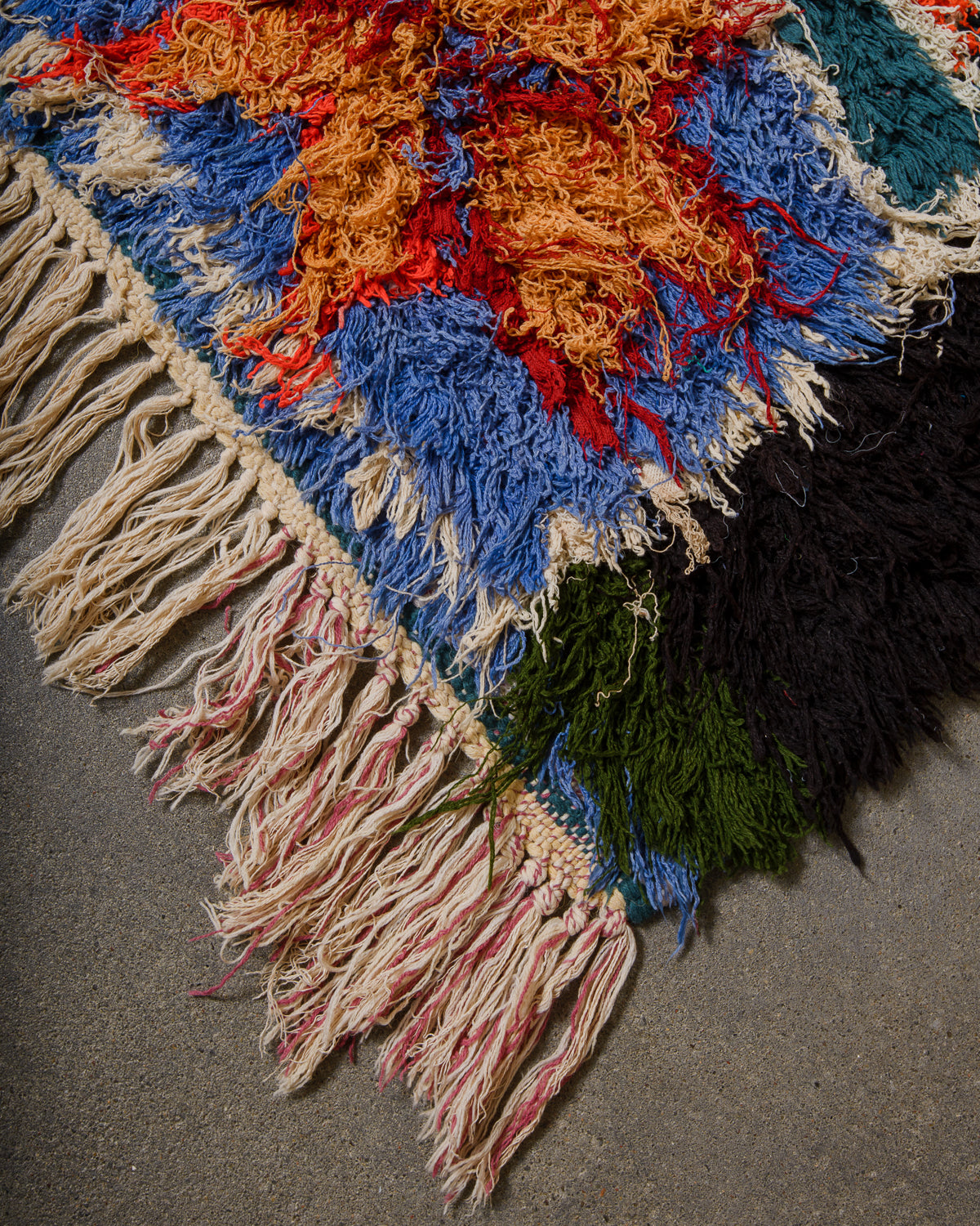Multicolored textured rug with fringes on a gray surface