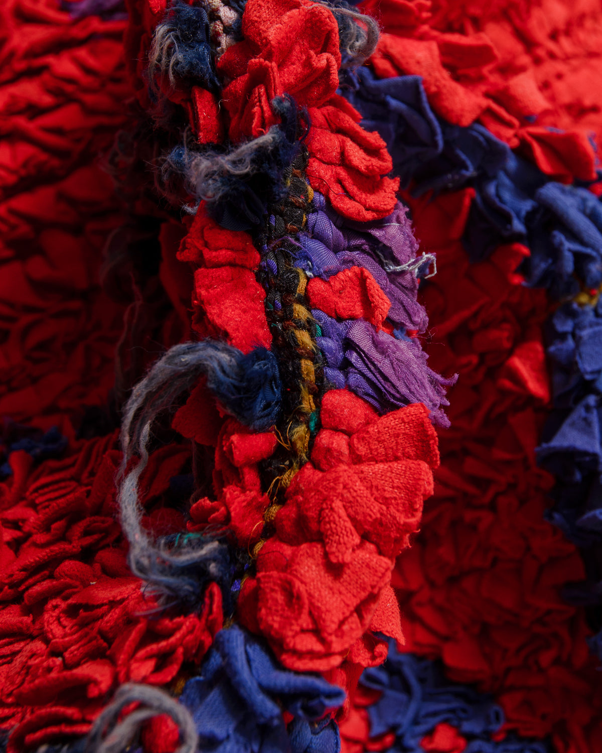 Close-up of a textured fabric with red, blue, and purple colors.