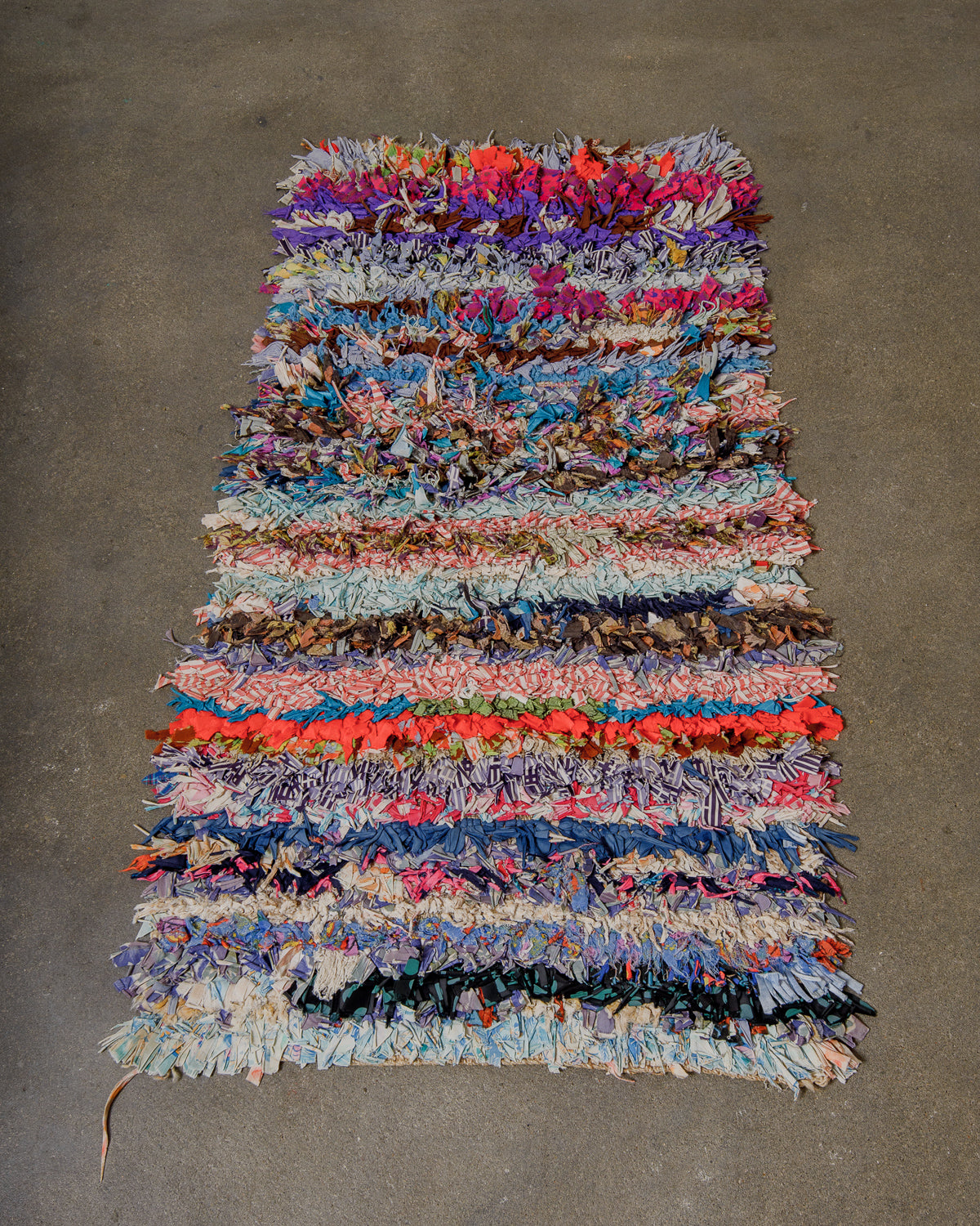 Multicoloured woven rug on a grey surface.