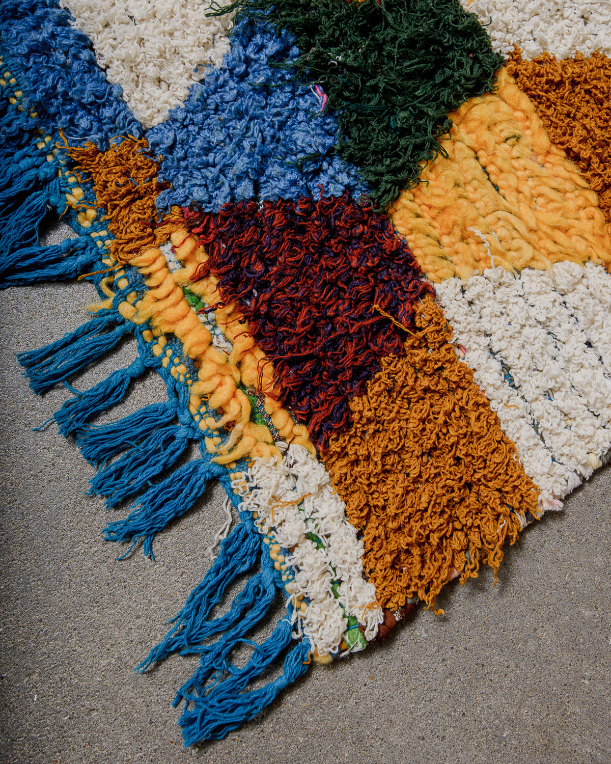 Multicoloured textured rug with fringes on a gray surface
