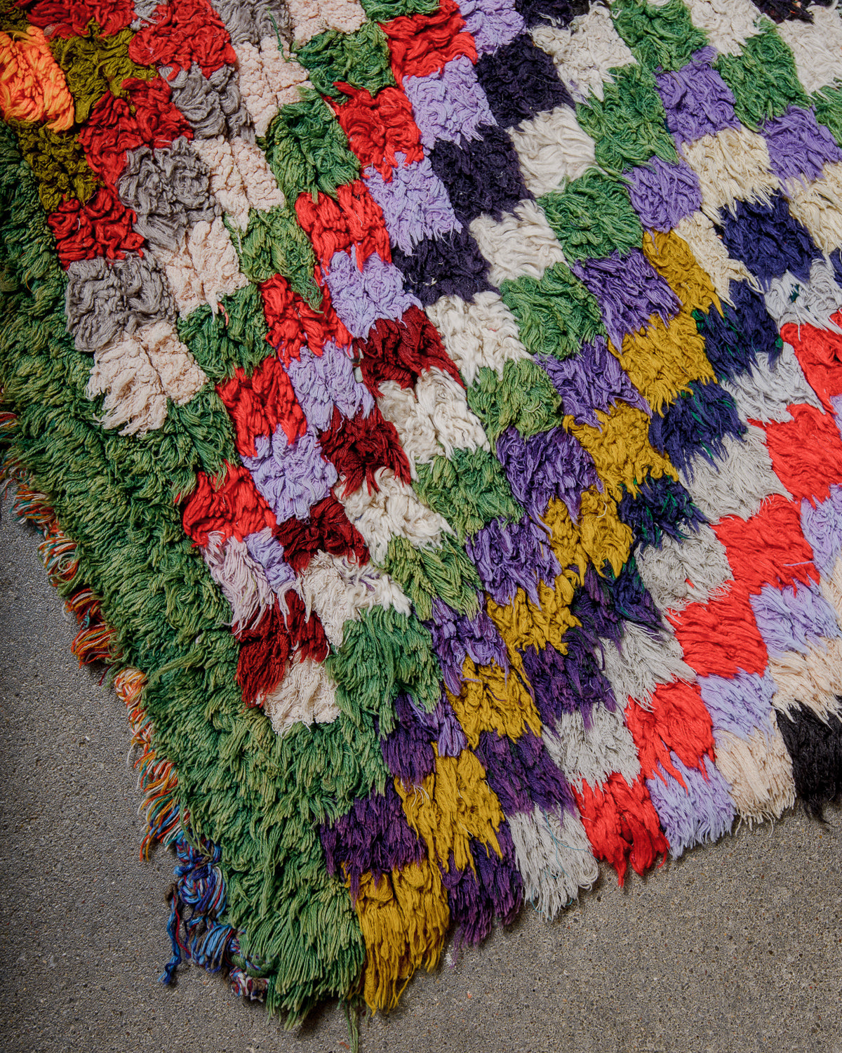 Multicoloured textured rug with a geometric pattern on a gray surface