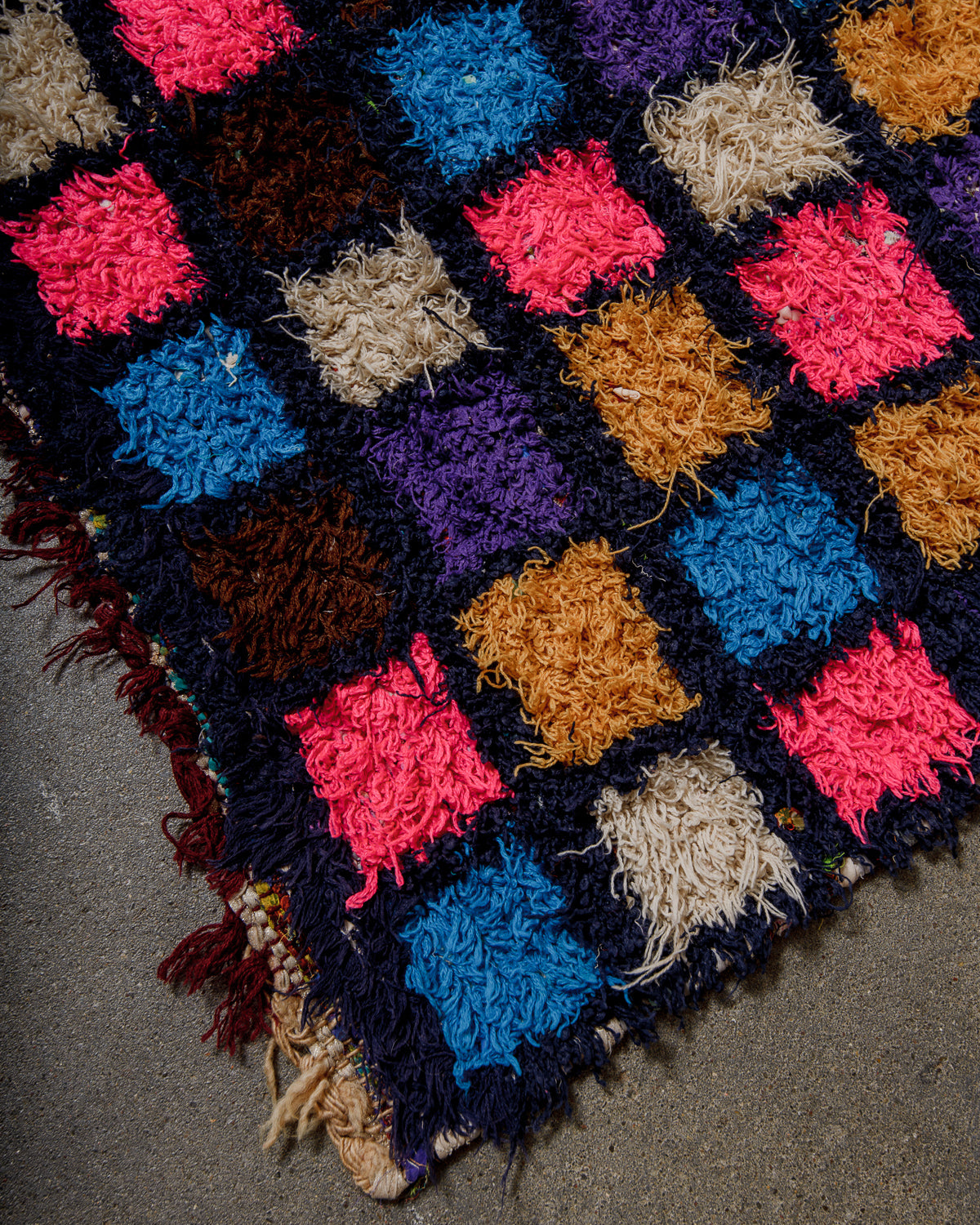 Multicoloured textured rug with a geometric pattern on a cement surface