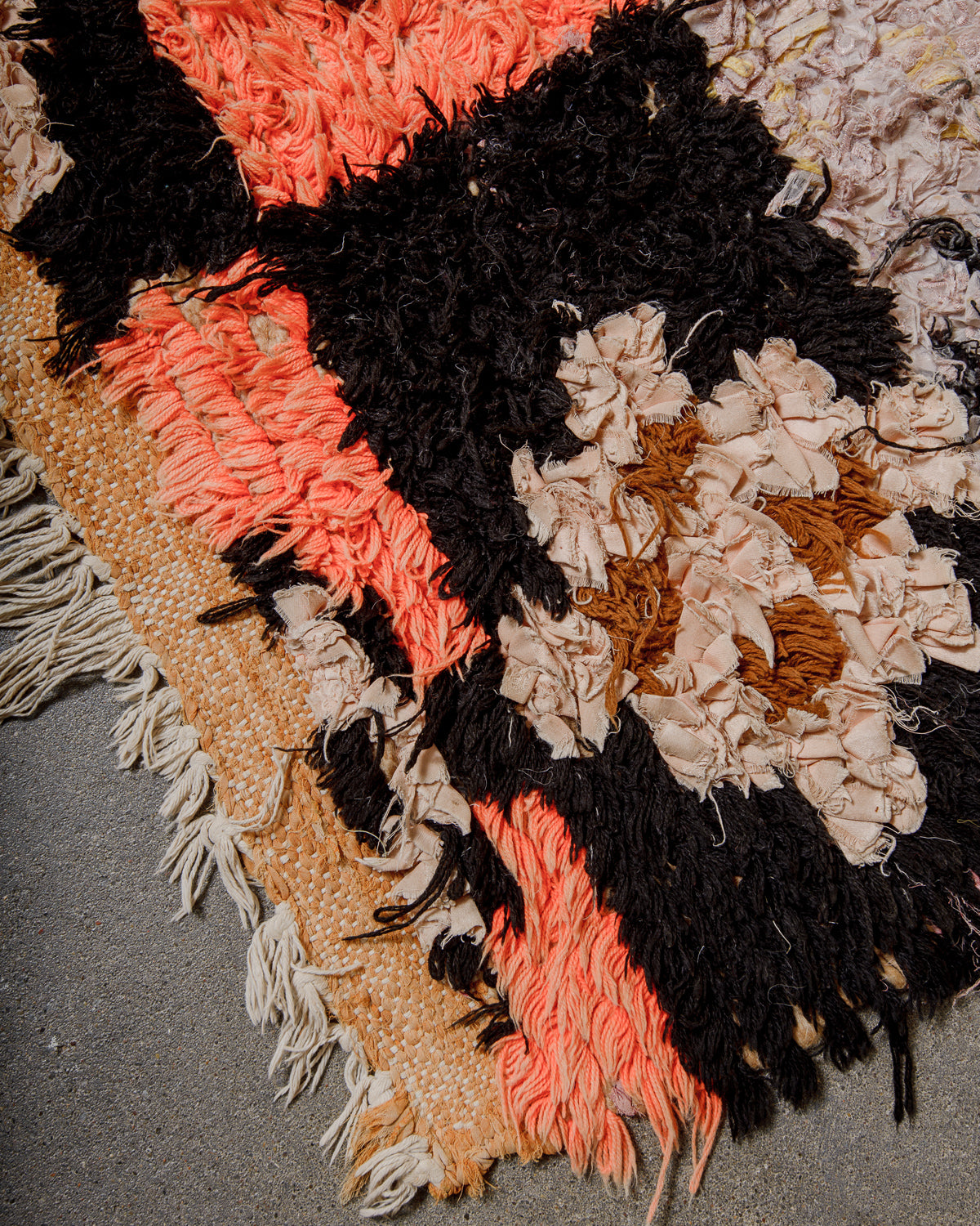 Corner of rug with made of colourful fabric scraps on a textured surface