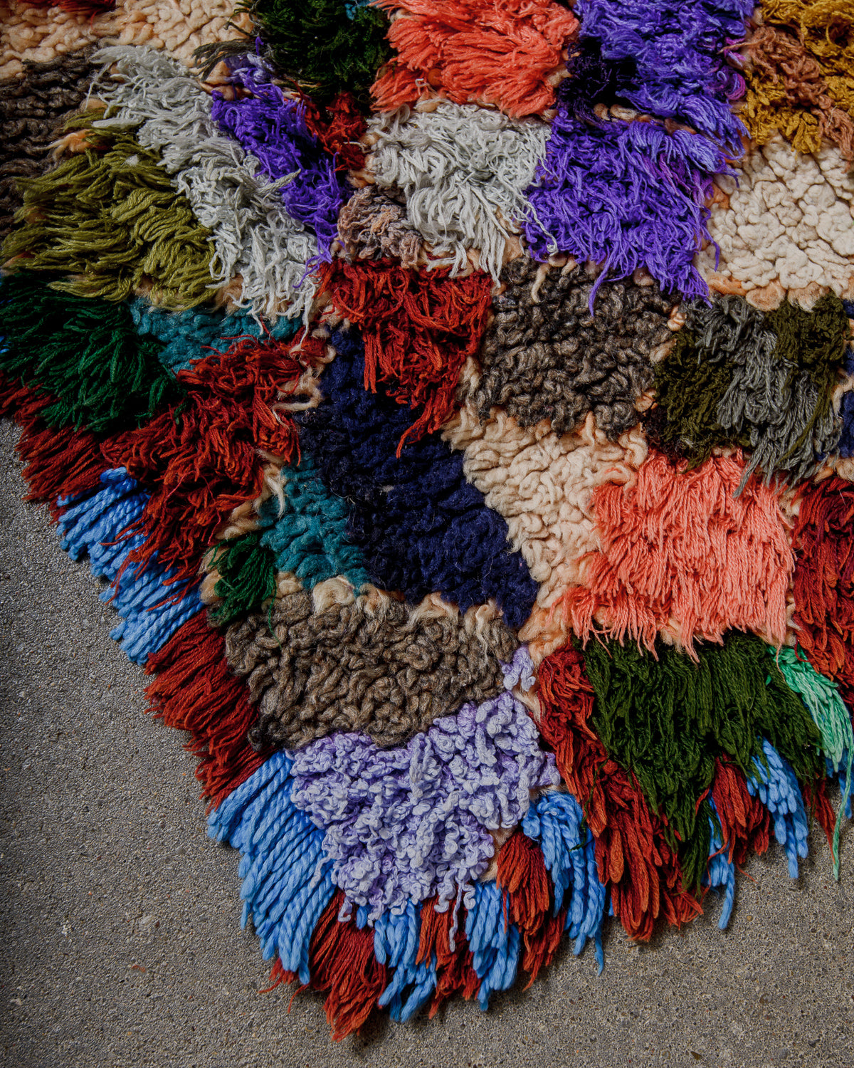 Colourful textured rug with a geometric pattern on a concrete floor.