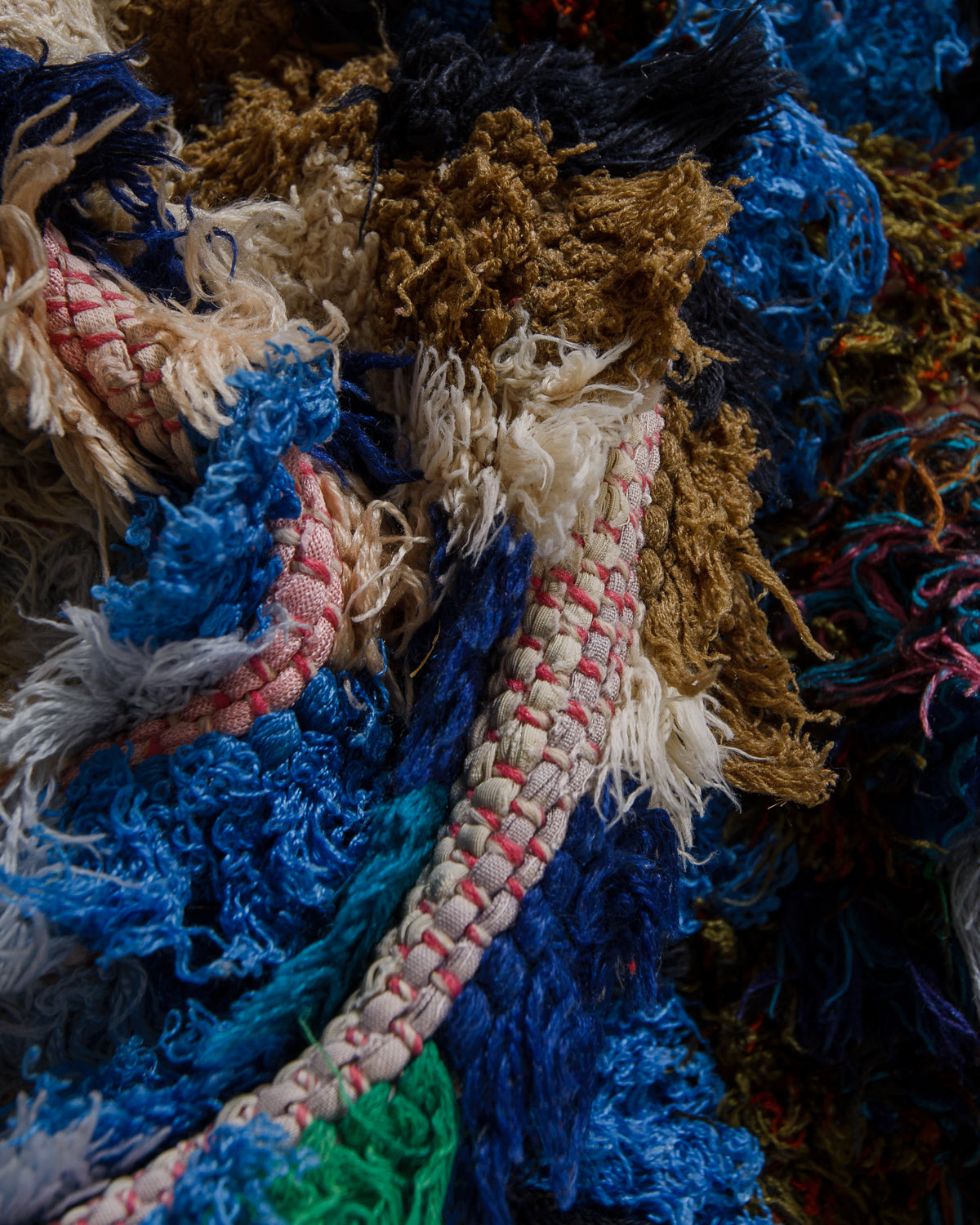 Close up showing wool, cotton and fabric remnants, in shades of blue and white, used to make up this Boucherouite "rag rug".