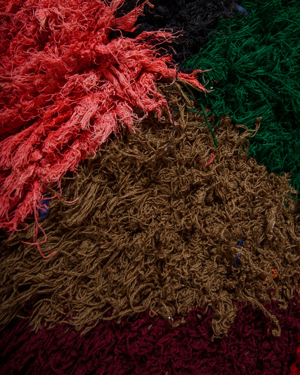 Close-up of textured fabric in various colors including red, green, brown, and purple.