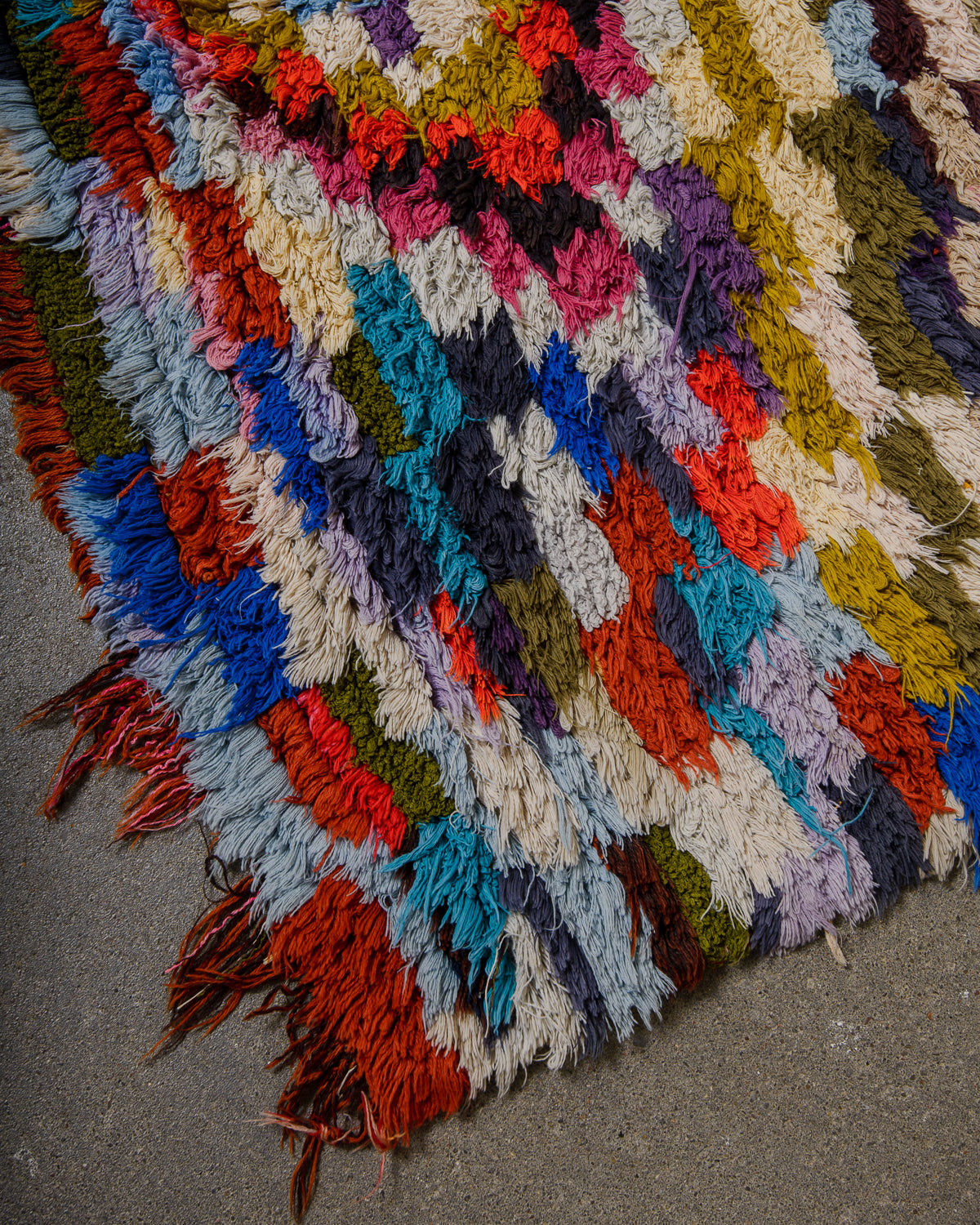 Multicolored textured rug with fringes on a gray surface