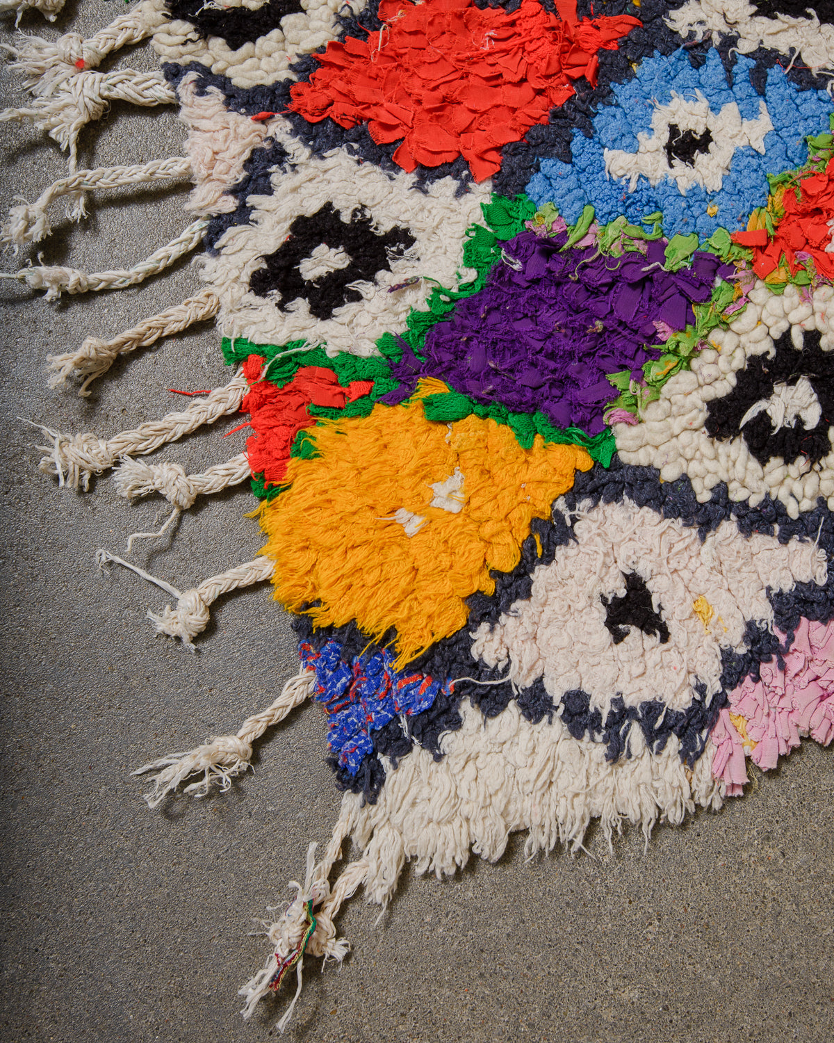 Colourful woven rug with geometric pattern on a gray surface