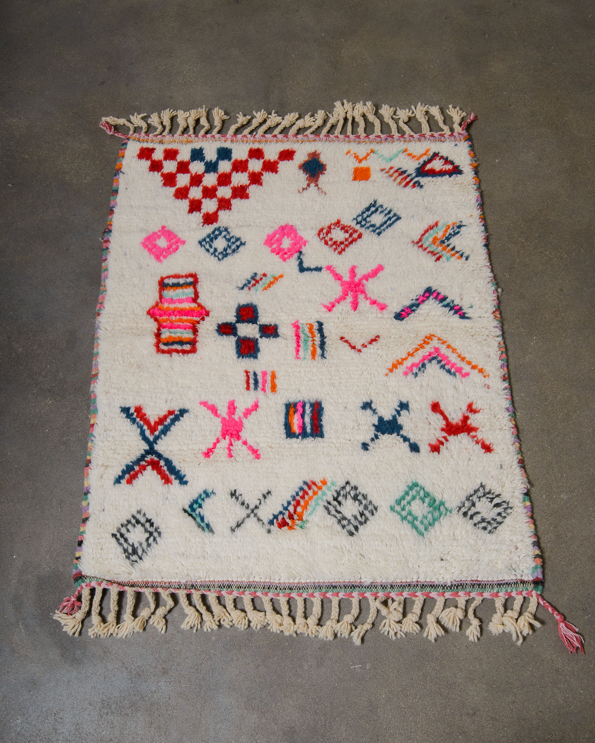 Colorful geometric patterned rug with tassels on a gray floor