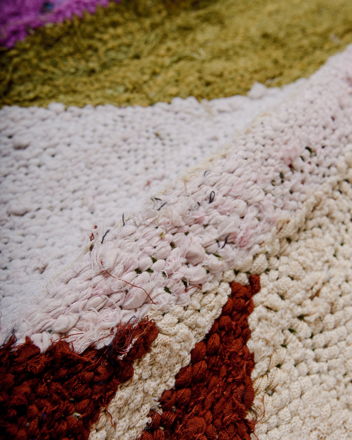 Different textures on the surface of a Berber Kelim rug in white, mustard and brown. 