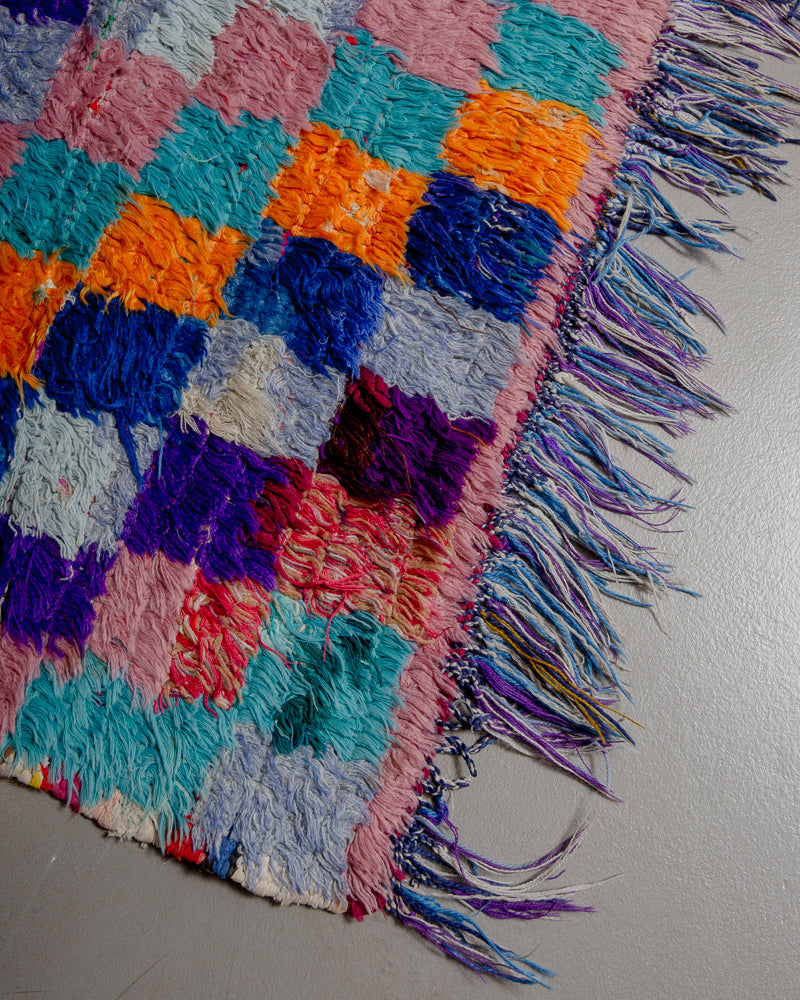 Corner of vintage rug with fringed edge.