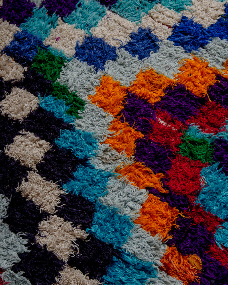 close up of surface of boucherouite rug with many coloured squares.