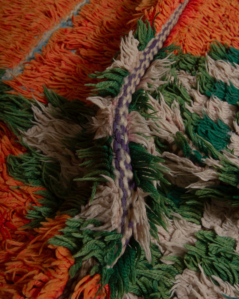 Close up of boucherouite rug with orange, green and white cotton.