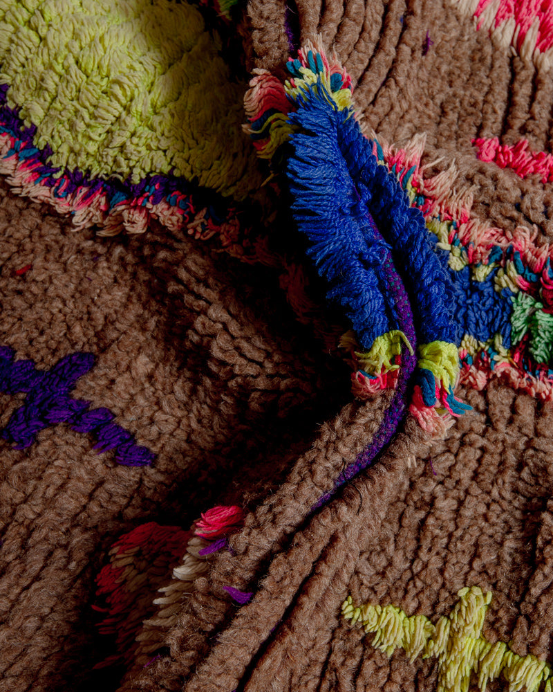 Close up of boucherouite rug with blue, yellow, purple and pink cotton and brown wool.