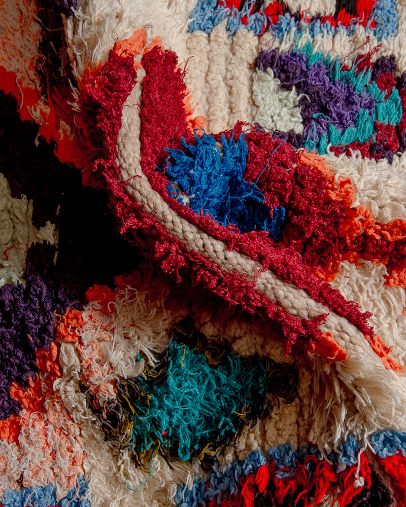 Close up of boucherouite rug with blue, red, purple and orange cotton and cream wool.