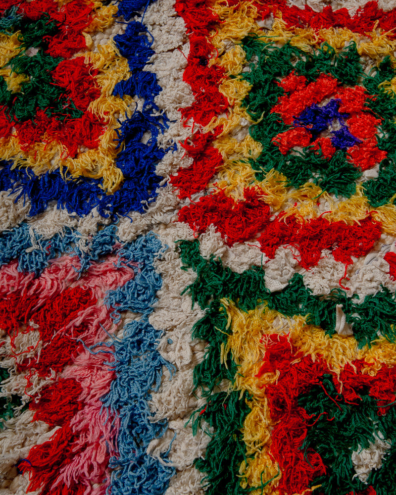 Surface of boucherouite rug with colourful yarn in red, yellow, green, blue, pink and white.