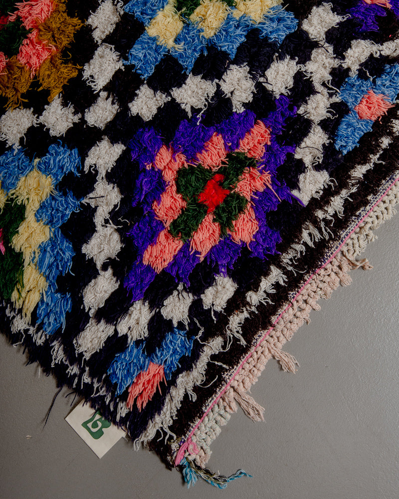 Corner of vintage rug with short tasseled edge.