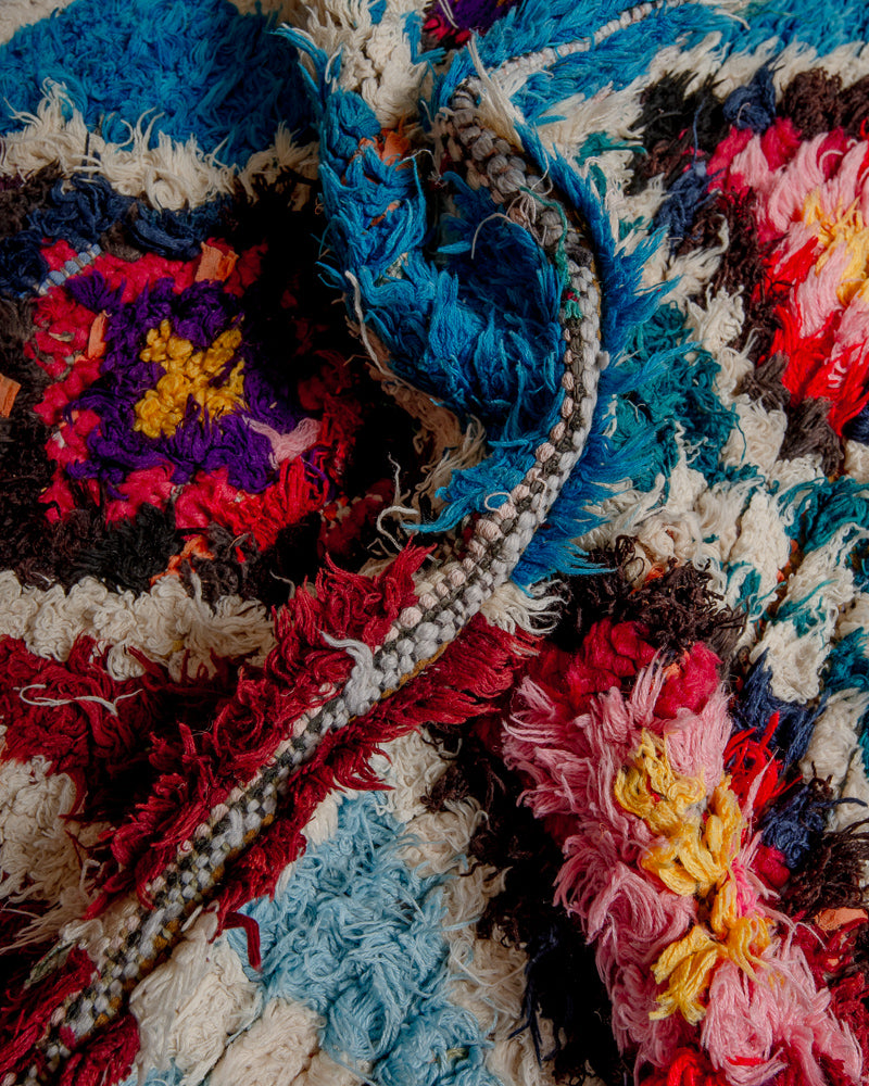 Close up of boucherouite rug with blue, red, purple and yellow, pink and white cotton.