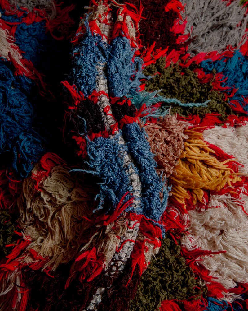Close up of boucherouite rug with red, blue, mustard and white yarn.