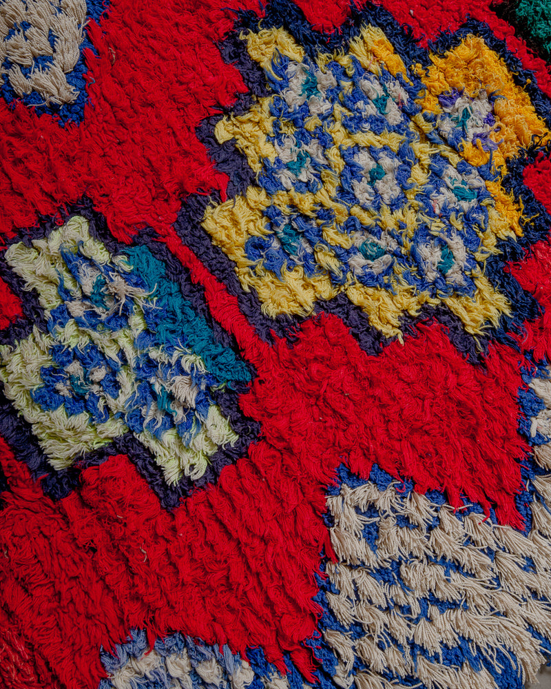Surface of boucherouite rug with red, blue yellow and purple yarn.