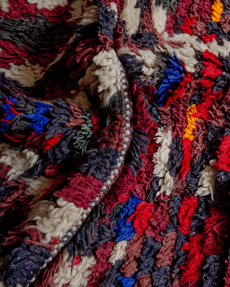 Close up of boucherouite rug with red, blue and grey cotton and cream wool.