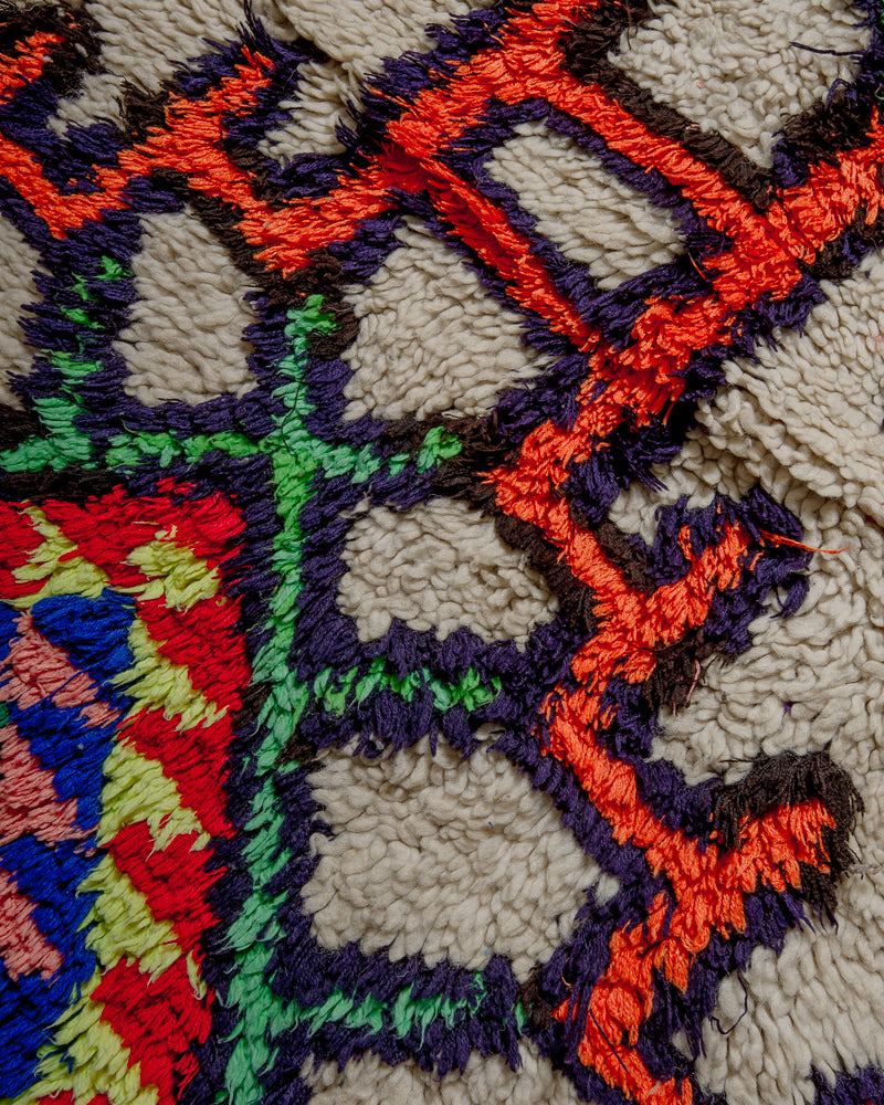 Surface of boucherouite rug with orange, blue, green and purple cotton and cream wool.