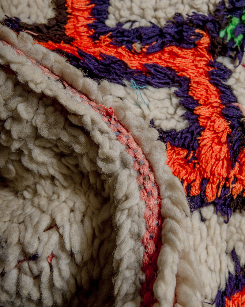 Close up of boucherouite rug with orange, and purple cotton and cream wool.